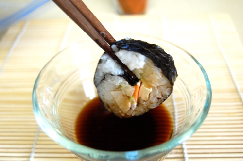 Dipping sushi in soy sauce with chopsticks